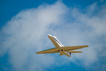 Fototapeta na wymiar Small Jet Airplane Flying Overhead in the deep blue sky