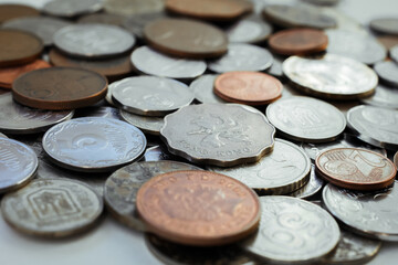 scattered coins from different countries lie on the surface of the table, selective focus, macro