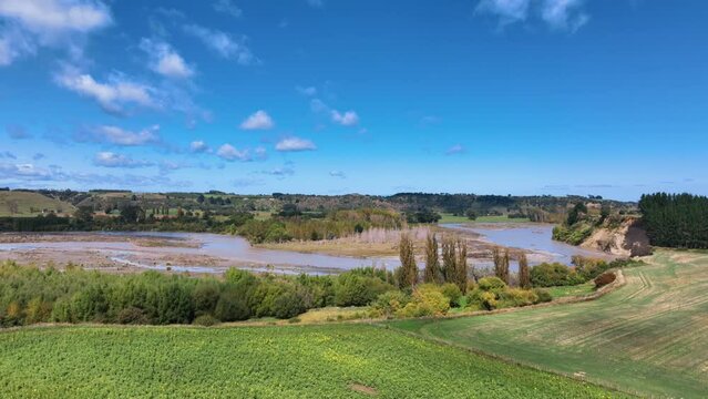 Fly towards flooded Rangitikei River over verdant farmland - New Zealand