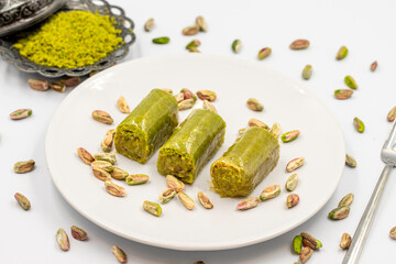 Baklava wrapped in pistachio on a white background. Traditional Mediterranean cuisine delicacies. close-up pistachio baklava. local name fistik sarma baklava