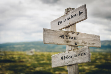 broaden your horizons text quote written in wooden signpost outdoors in nature. Moody theme feeling.