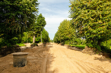 Street repair in summer day. Sand, sewage well and trees.