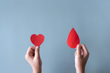 Blood donation or surgery concept. Human holding blood sign and a red heart shape.