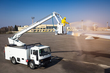 The specialist treats the aircraft with antifreeze at the airport. The process of spraying de-icing liquid on an airplane wing at an airport