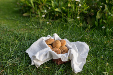 Composition of buns in basket with white white cloth napkin on the green grass