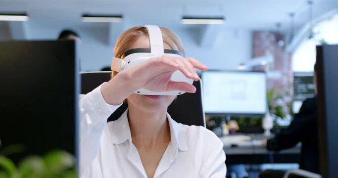 Close up of Caucasian woman in VR glasses sitting in office and moving hands in air. Female in headset tapping and scrolling in space. Virtual reality. Augmented gaming. Gamer. Coworking center.