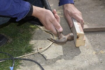 A man hammers a nail into a wooden door frame.