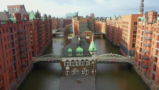 Old red-brick buildings in Speicherstadt along a canal with bridges. Flight through the Warehouse district, downtown in Hamburg, Germany. Aerial drone view. 4K 