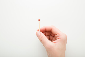 Young adult woman fingers holding match stick on white background. Closeup. Top down view.