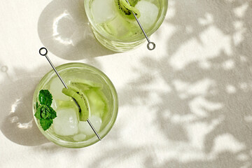 Summer cold drink and beverages. Lemonade with kiwi, mint  and ice in glass. Rinfreshment unalcolic cocktail. Selective focus.