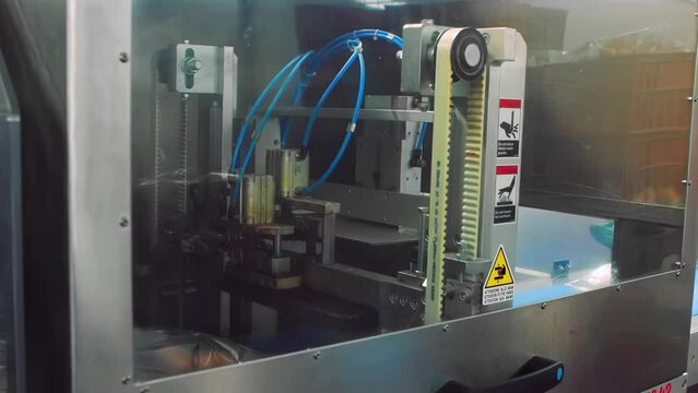 Industrial meat processing plant factory. Automated machine tool for vacuum packaging of food boiled sausage semi-finished products in plastic on conveyor belt in production line, workshop