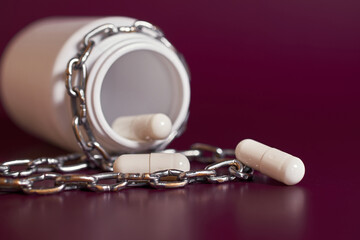Drug addiction. A jar with white capsules rewound by a chain 