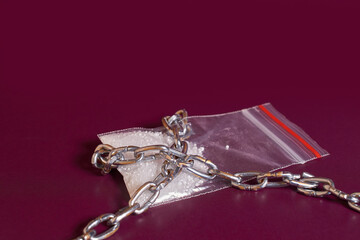 Drug addiction. A bag of white powder is rewound crosswise with a chain 