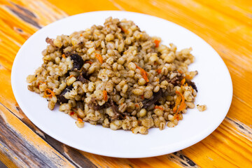 pearl barley porridge with mushrooms on a white plate