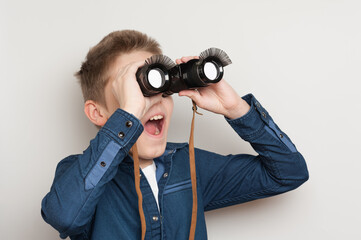 cheerful boy looking through binoculars with funny false eyelashes