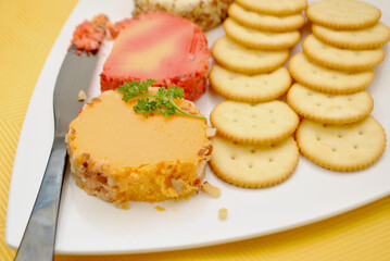 Cheddar Cheese Log Slices on a Plate with Round Crackers	After Being Picked At