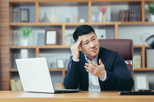 Businessman worried about business, sad and frustrated sitting in the office, looking anxiously at the laptop screen