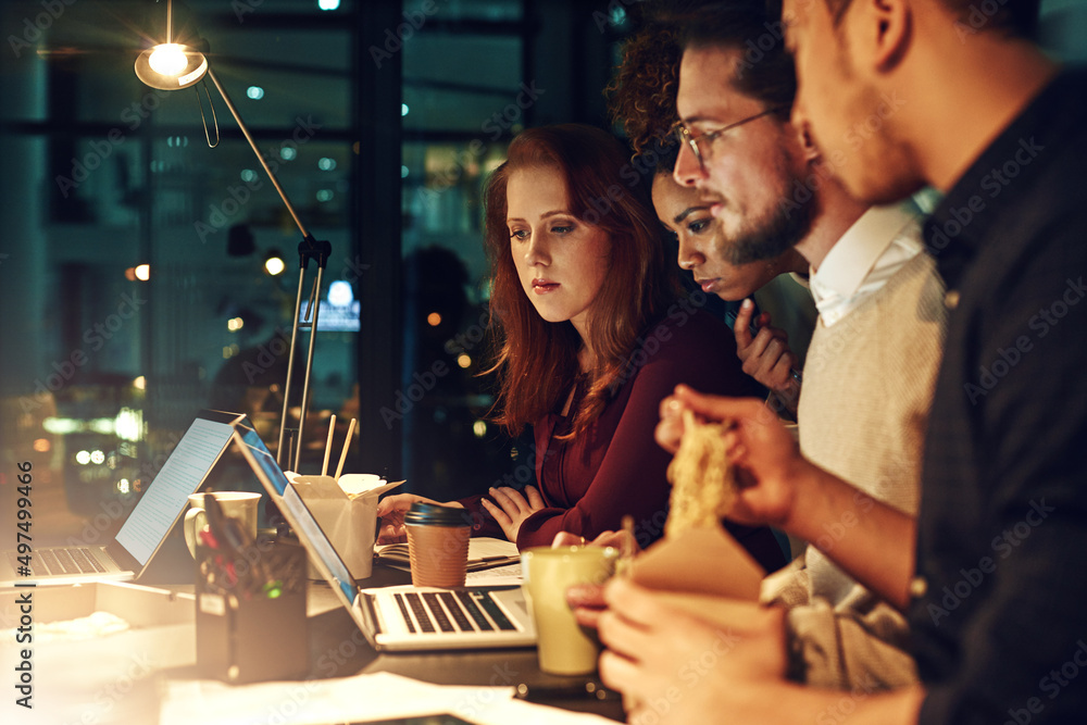 Poster Deadlines wait for no one. Shot of a business team using a laptop together on a night shift at work.