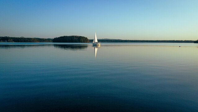 Sailing boat on the smooth water surface against the blue sky. Steinberger See, Germany.