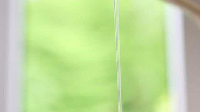 running water flowing from stainless faucet tap with two holes for drinking clean water in kitchen. green natural background, falling splashing stream ow water. economy concept home budget efficiency