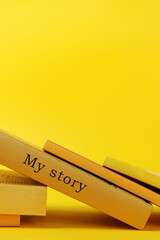 Yellow books on vibrant yellow background. One book with words my story written on book spine.