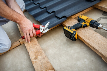 Roofers cut a metal tile using cutting pliers