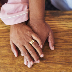 Together always. High angle closeup of an unrecognizable couple holding hands on a table at home during the day.
