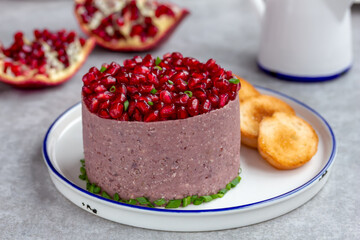 Bean, walnut, and pomegranate pate served on a plate with homemade croutons. Healthy vegetarian starter or part of a party platter. Close up, horizontal, selective focus.