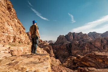 tourist looks at the red rocky mountains in jordan - obrazy, fototapety, plakaty