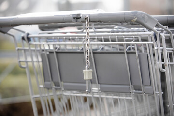 chain connector on a shopping cart .hang on grip next to coin slot is a mechanism you have to insert a coin on deposit to release trolley from the row where the metal baskets are nest to each other