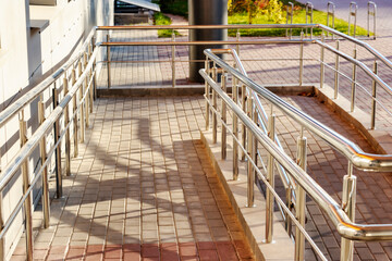 A ramp and metal railings at the entrance to the residential building for the convenience of people...