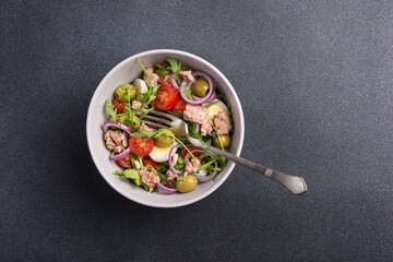 Healthy tuna salad with fresh arugula, cherry tomatoes, quail egg and olives