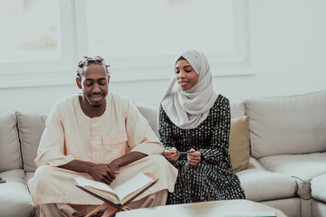 African Muslim couple at home in Ramadan reading Quran holly Islam book.