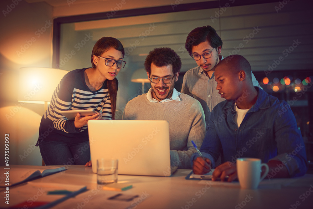 Poster reaching for all the success they can get. shot of a group of designers working late in an office.