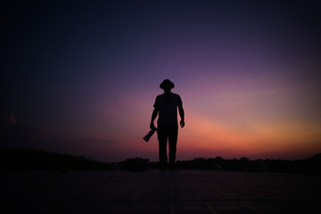 Photographer's silhouette walking down the camera direction in the golden hour