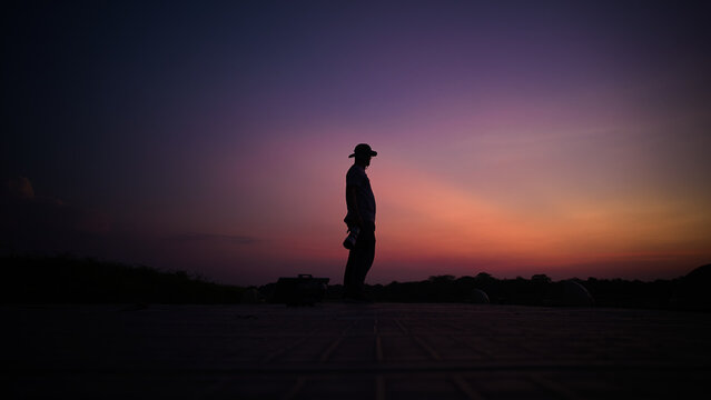 Photographer's silhouette with glasses standing still watching the horizon in the golden hour