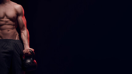 Sun-tanned strong focused fit muscular man with big muscles holding heavy kettle bell for swing training hard core workout in the gym