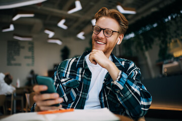 Young caucasian guy using smartphone at table