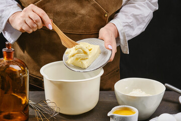 The female hands of the cook are preparing a culinary product, dough. Shift the butter into a large bowl. Shallow depth of field	
