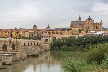 Fototapeta na wymiar View at the Roman Bridge over Guadalquivir river, Mosque-Cathedral of Córdoba, Roman Catholic Diocese and Plaza del Triunfo as background, Cordoba downtown, Spain