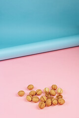 delicious walnut shaped shortbread sandwich cookies filled with sweet condensed milk and chopped pistachio nuts on brown clay dish. on pink background, view from above, close-up