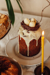 Traditional Ukrainian Easter cake decorated with a nest with eggs and a candle. Traditional dessert. Easter cake stands on a festive table decorated with sweets.