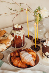Traditional Ukrainian Easter cake decorated with a nest with eggs and a candle. Traditional dessert. Easter cake stands on a festive table decorated with sweets.