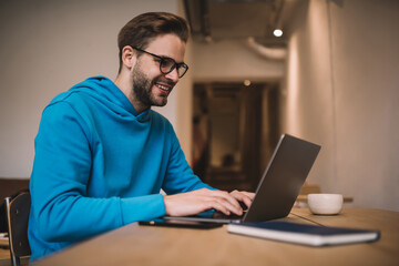 Happy Caucasian freelancer browsing web design on modern laptop computer, smiling IT professional...