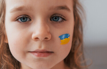 Close up view. Portrait of little girl with Ukrainian flag make up on the face