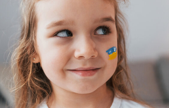 Smiling and having good mood. Portrait of little girl with Ukrainian flag make up on the face