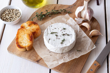 Camembert cheese with garlic, thyme and toasted bread. French cuisine.