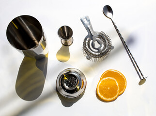 Top view of barware for making cocktails with orange slices on a white background