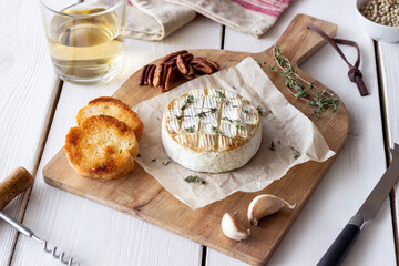 Baked Camembert cheese with garlic, thyme and toasted bread. French cuisine.