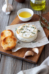 Baked Camembert cheese with garlic, thyme and toasted bread. French cuisine.
